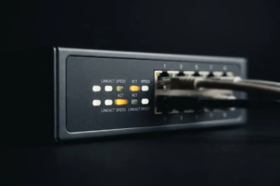 A close-up of a network switch with active status lights, representing the always-on website security firewall
